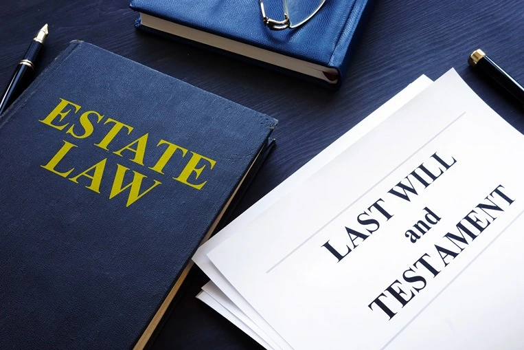Essential documents for estate planning such as a blue estate law book and a last will and testament document.