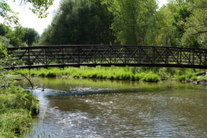 Bridge over a calm river surrounded by lush greenery, representing tranquility and nature in Lakewood, Colorado, relevant to estate planning and family connections.