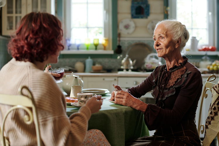 Two women engaged in a heartfelt conversation over tea at a kitchen table, discussing estate planning and family matters.